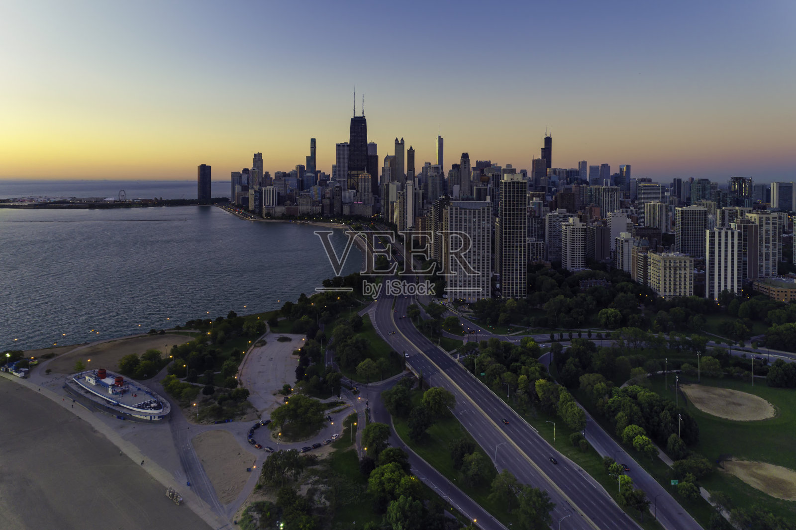 暮色中的芝加哥天际线。沿着海滩和密歇根湖通往城市的路照片摄影图片