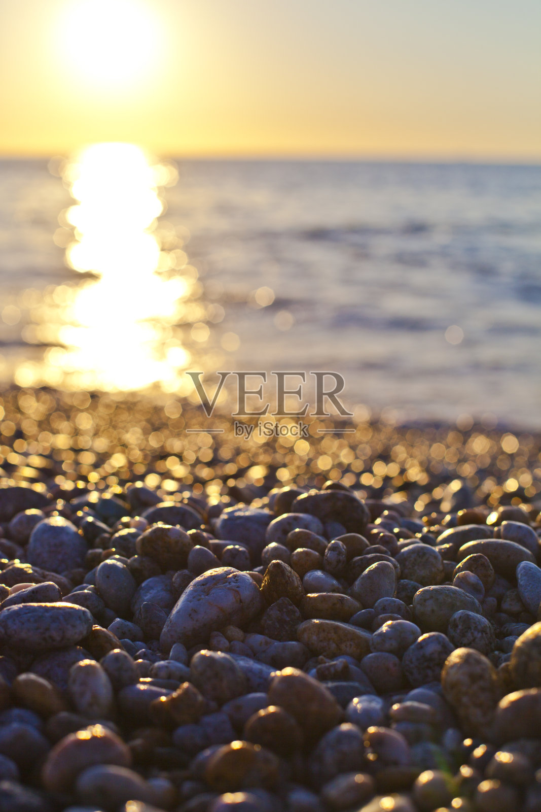 美丽的海景，在柔和的日落光线下，令人惊叹的卵石海岸线。照片摄影图片