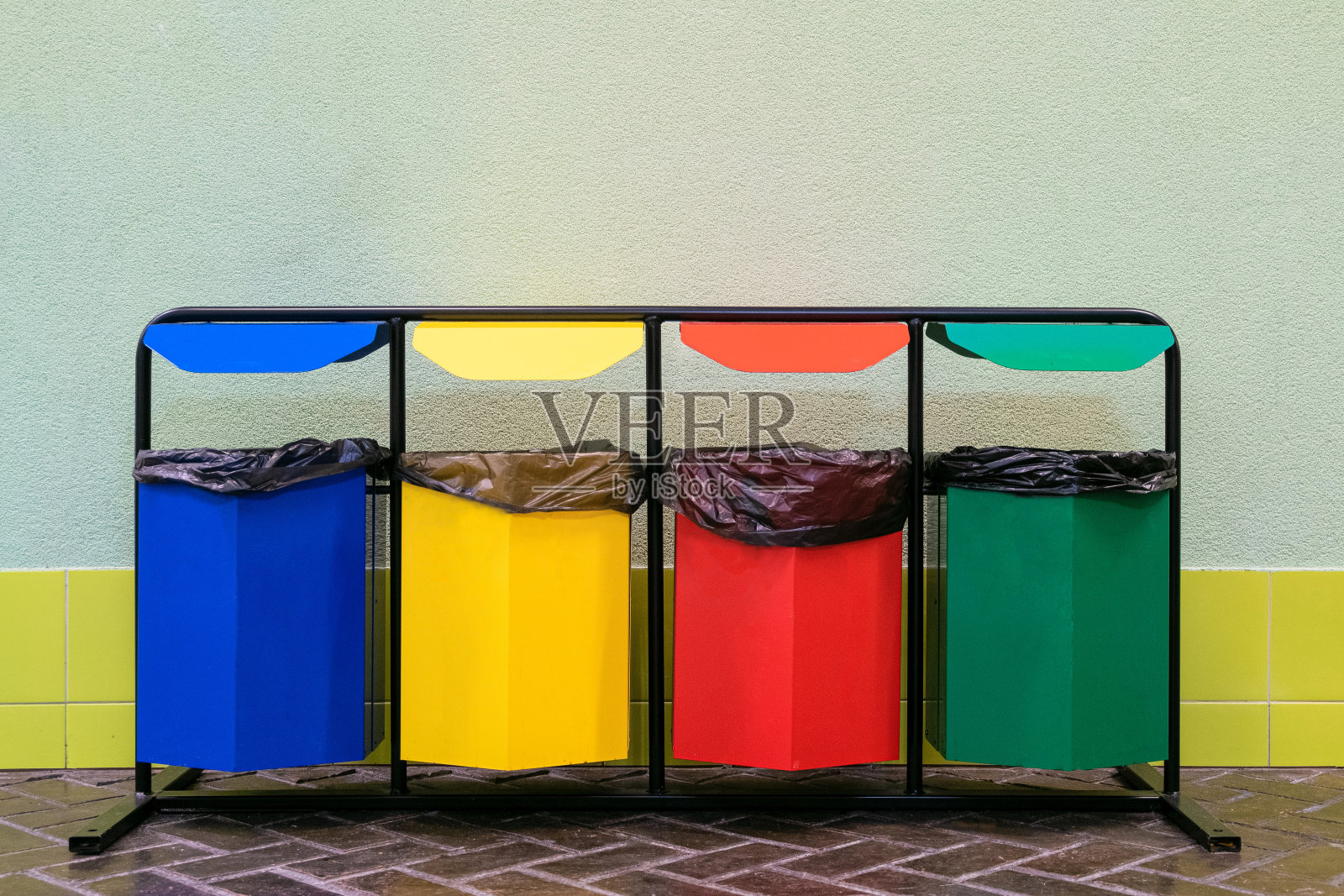 四个不同颜色的垃圾桶，用于分类垃圾。玻璃、金属、纸张和塑料分开收藏。照片摄影图片