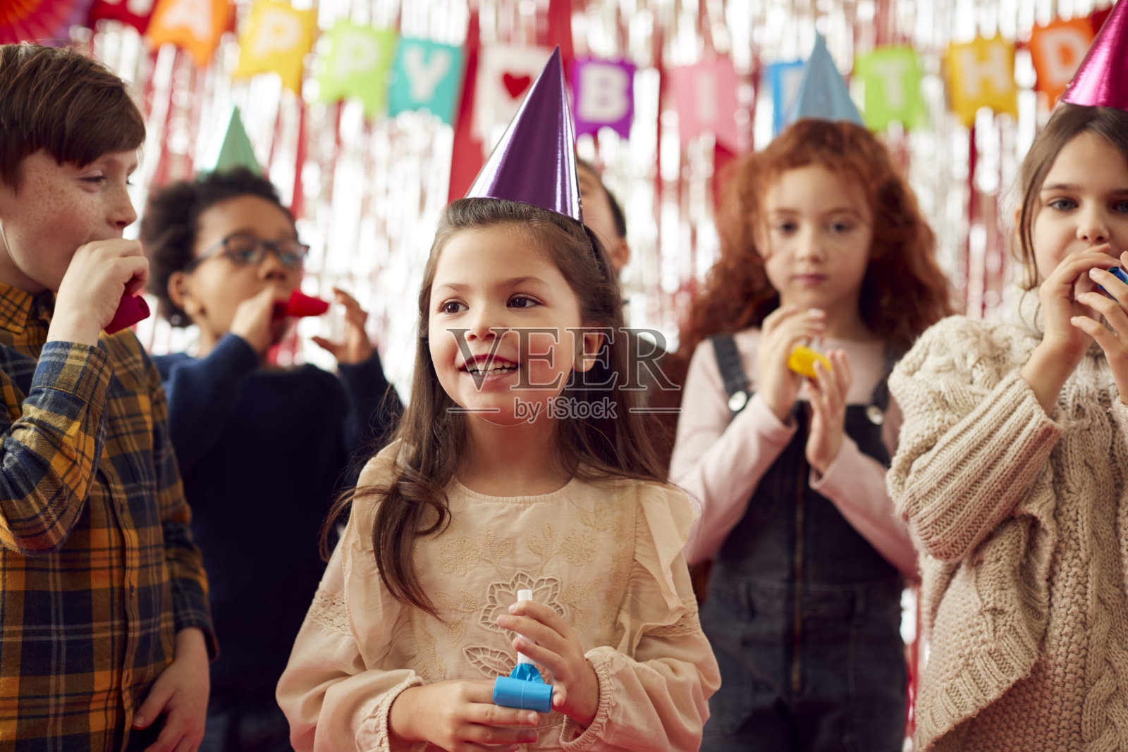 一群孩子在生日派对上用纸帽子和吹风机庆祝照片摄影图片