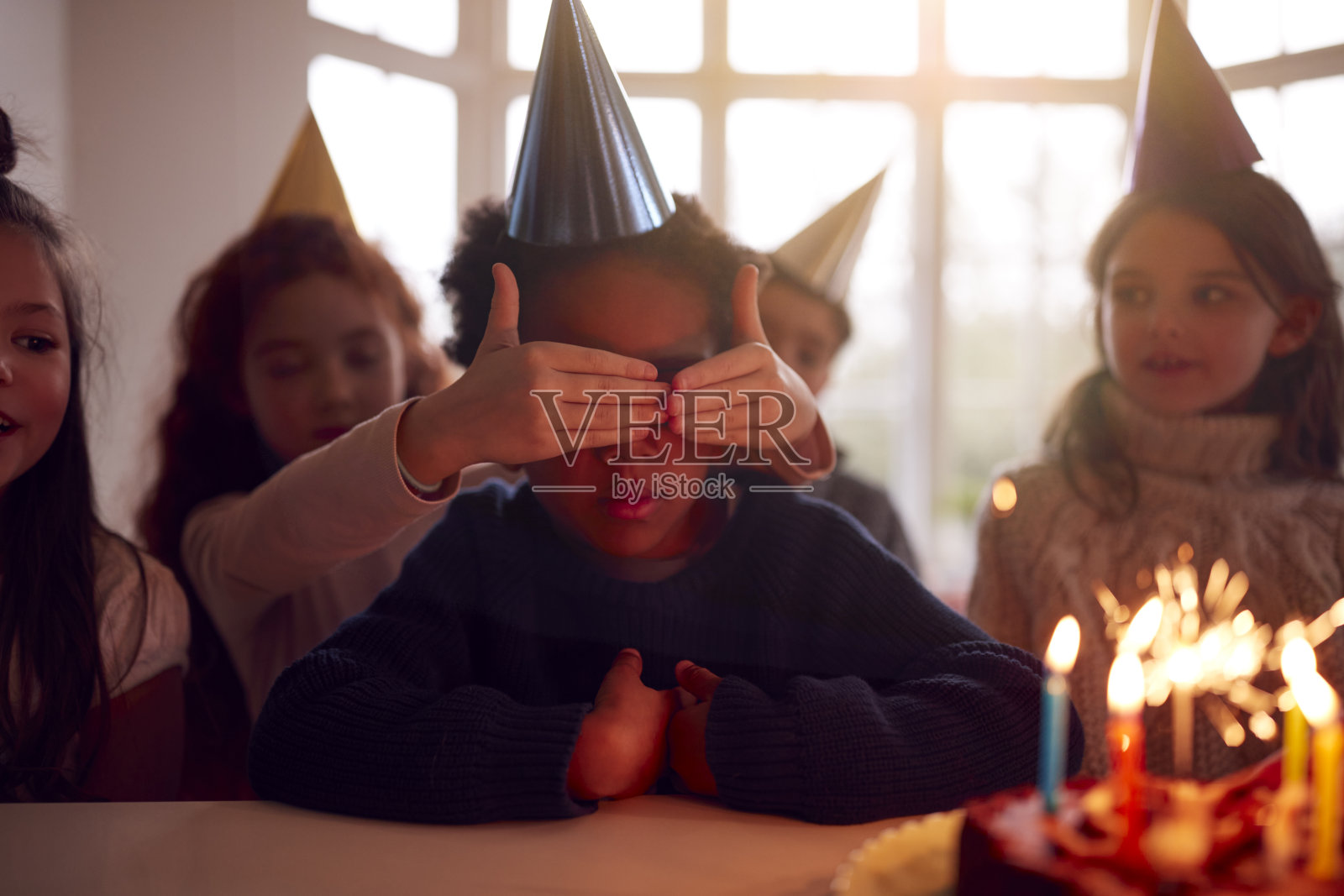 男孩和一群朋友在家里庆祝生日，收到装饰有烟火的蛋糕照片摄影图片
