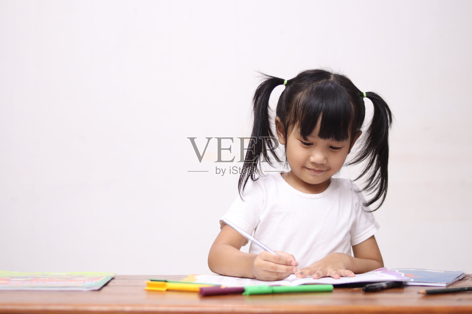 快乐聪明可爱可爱的亚洲小女孩画在书桌上，教育创造力的童年照片摄影图片