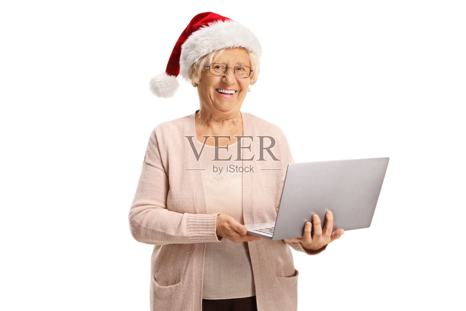 快乐的老妇人拿着笔记本电脑，戴着圣诞老人的帽子照片摄影图片