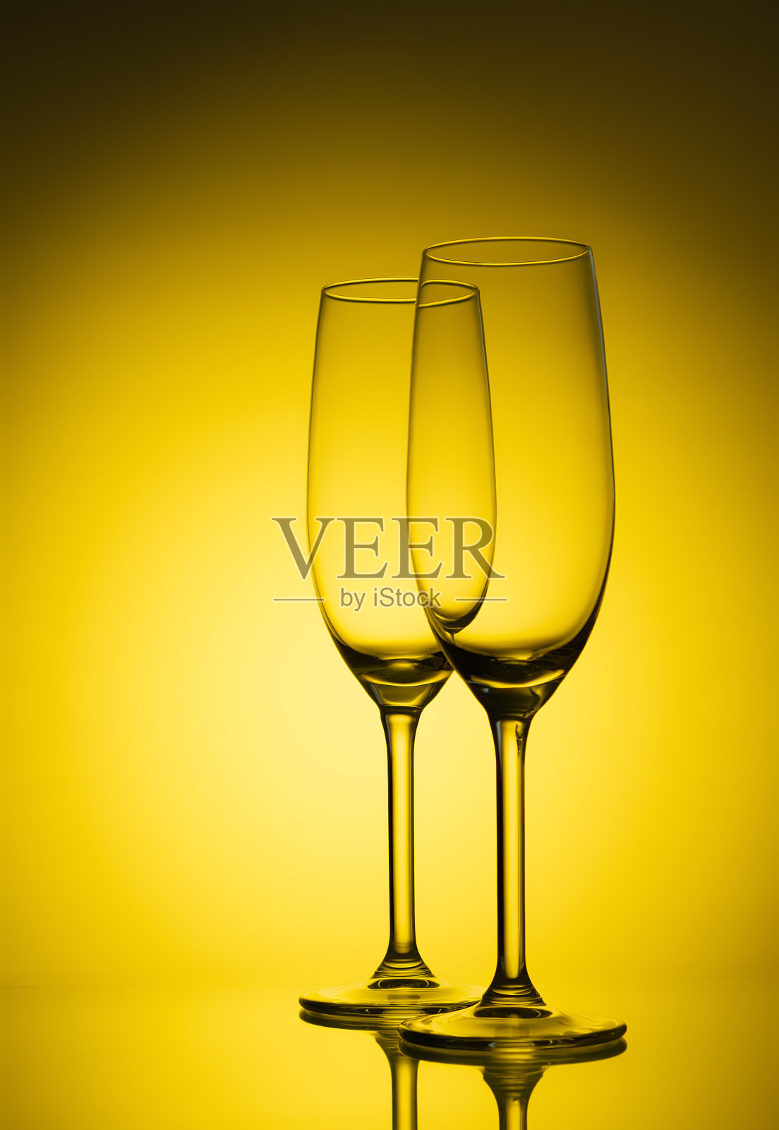 黄色背景上的两个空香槟杯。黄色灯光下的豪华酒杯。照片摄影图片