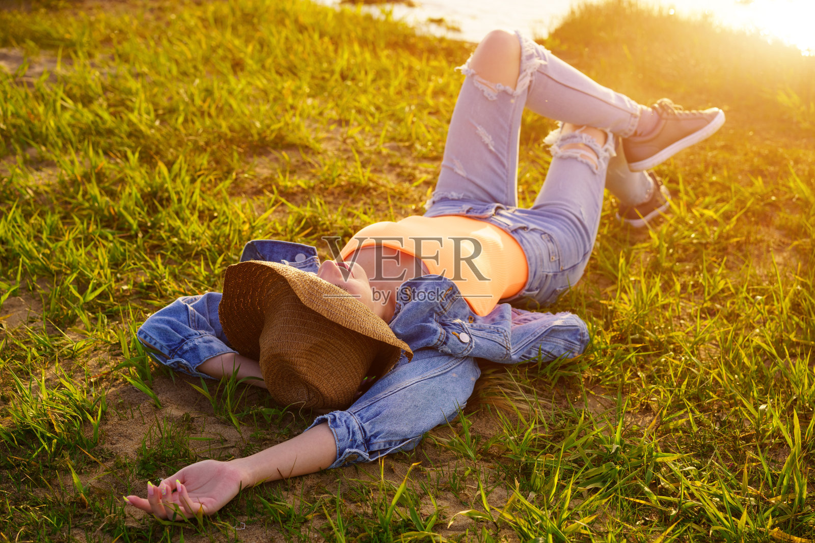 在一个阳光明媚的夏日，女孩躺在河边的绿草地上照片摄影图片
