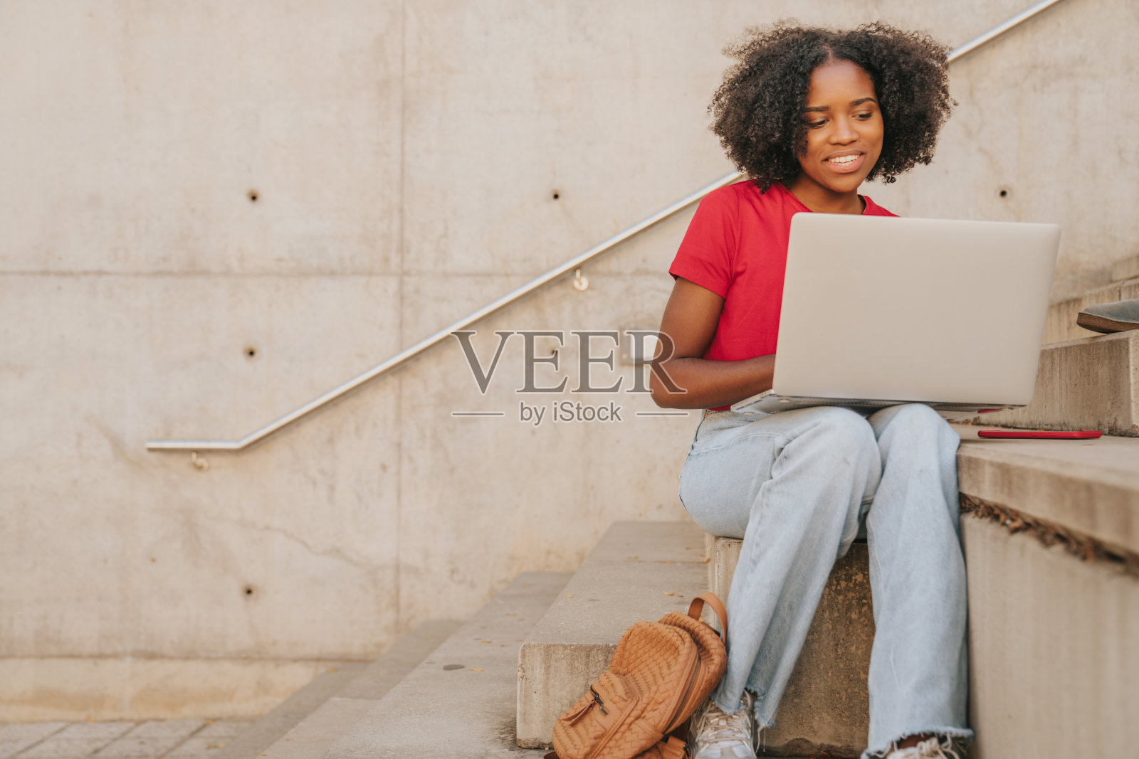 放松的年轻非洲妇女坐在外面与她的笔记本电脑照片摄影图片
