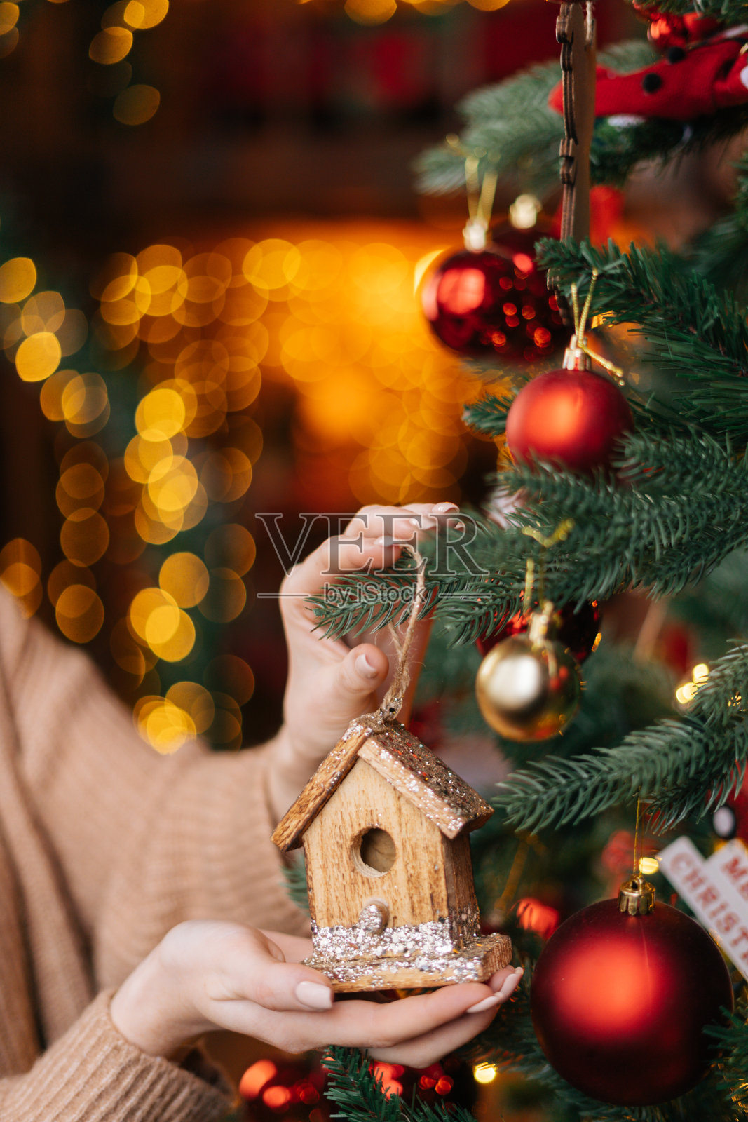 近距离的手，不认识的女人拿着圣诞玩具在圣诞树的背景。照片摄影图片