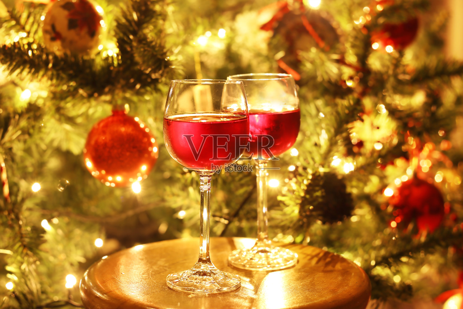 在圣诞前夜的圣诞树前用酒杯盛着红酒照片摄影图片