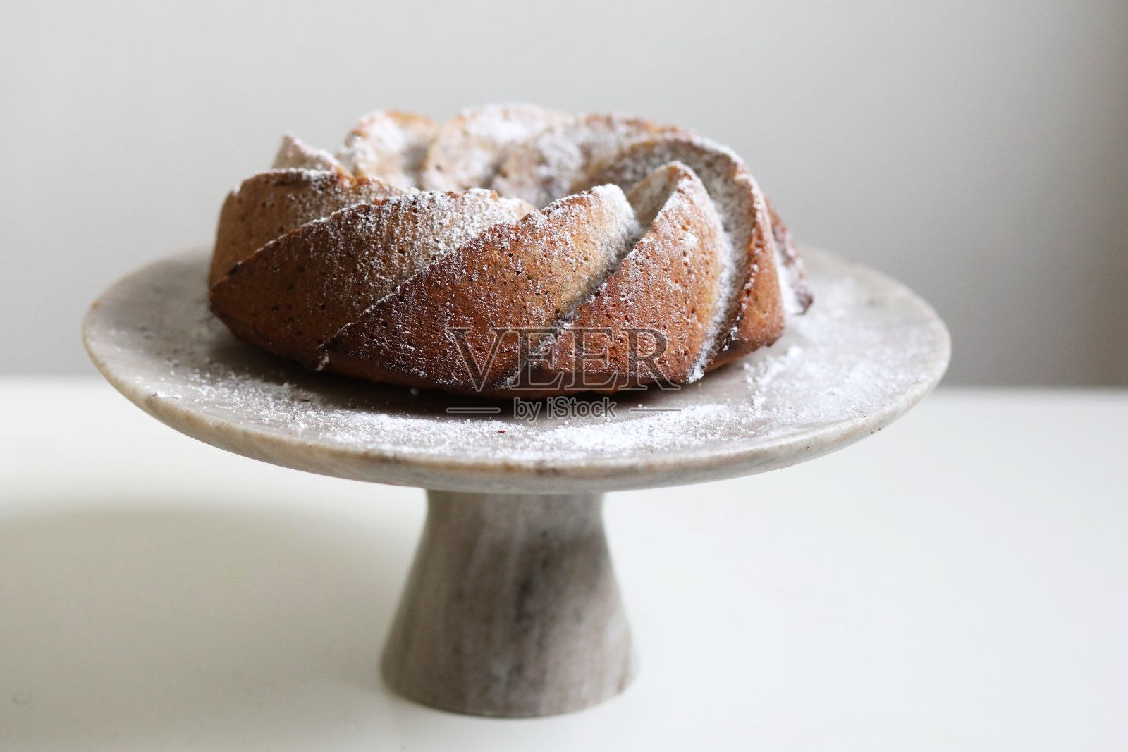 白色的桌子上放着自制的糖粉蛋糕。照片摄影图片
