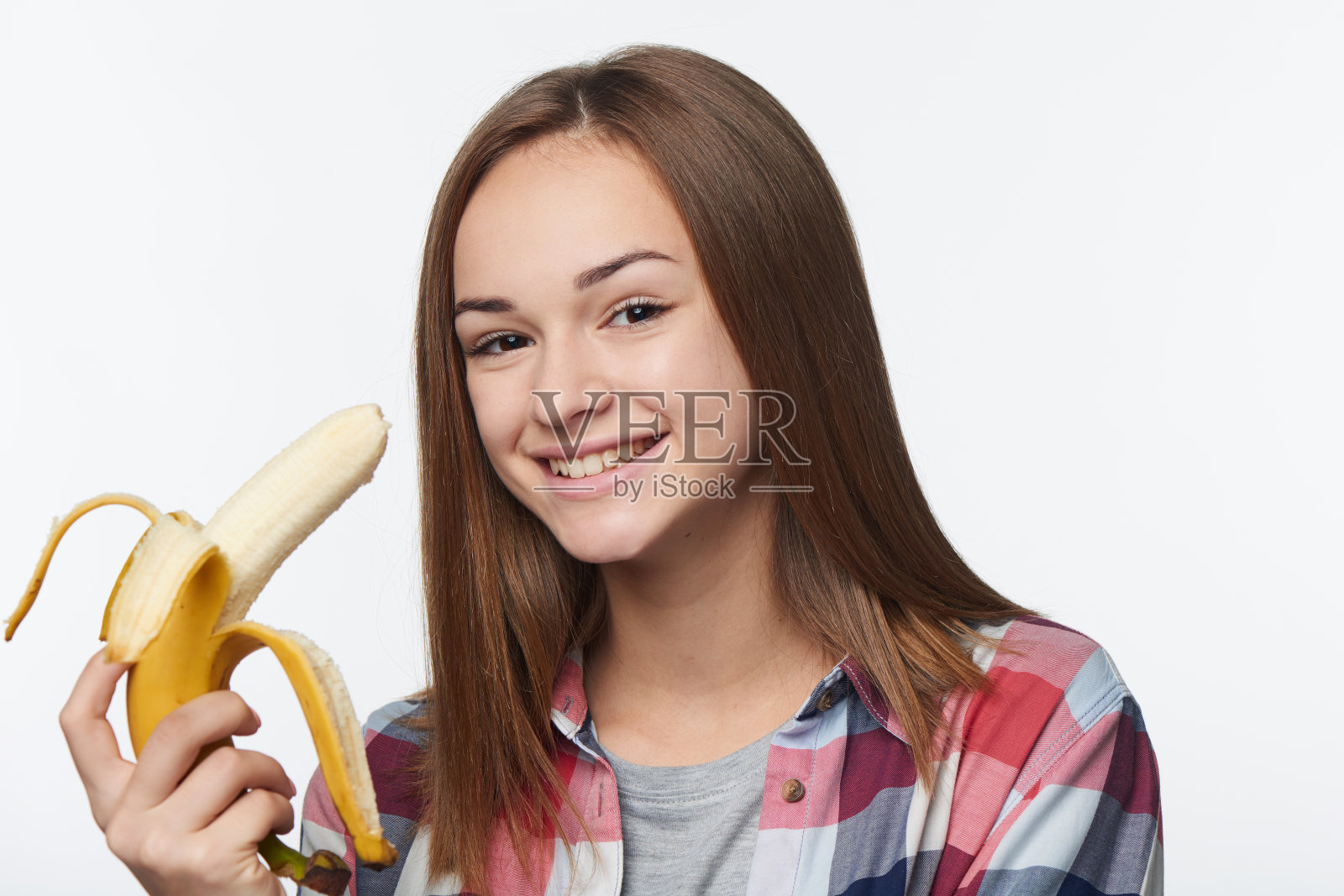 一个十几岁的女孩拿着半剥了皮的香蕉的肖像照片摄影图片