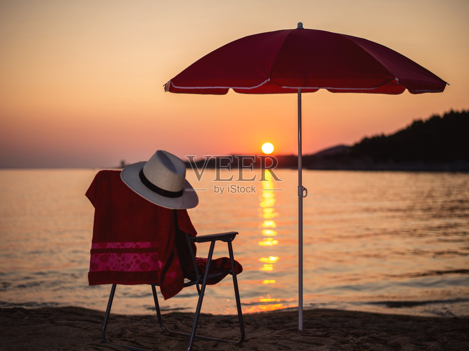 日落时分的热带海滩，配有沙滩椅和雨伞照片摄影图片