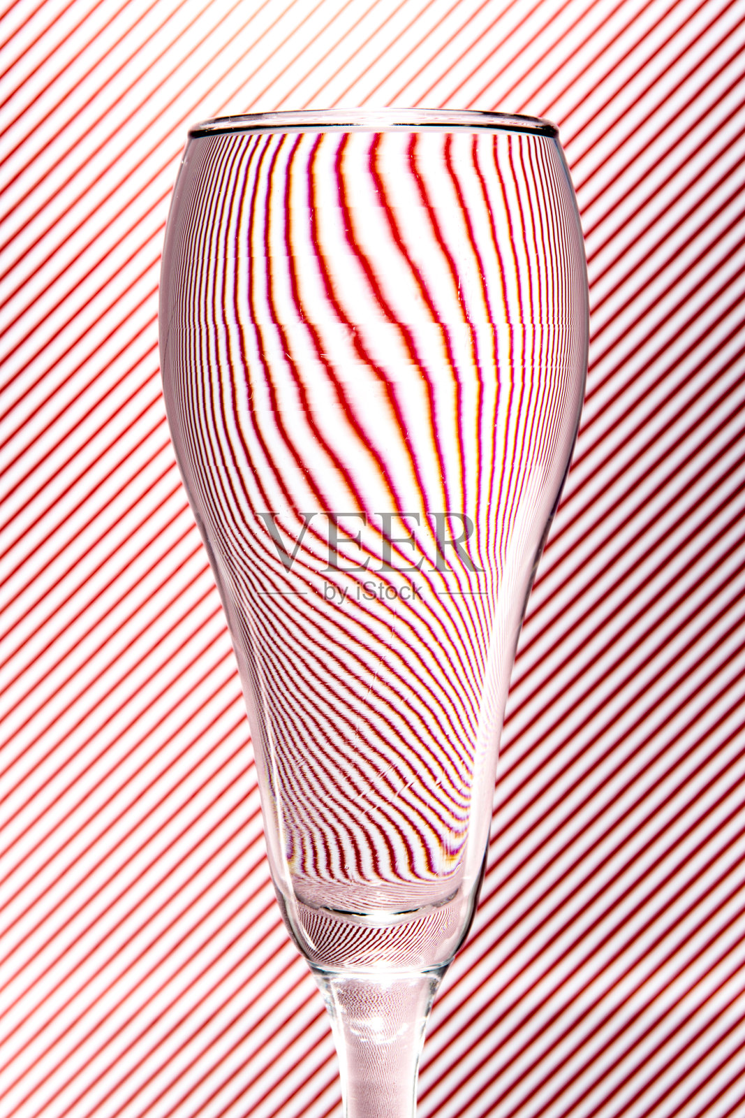 在红白条纹的背景上，酒杯折射的光线。抽象的玻璃艺术。情人节的概念照片摄影图片