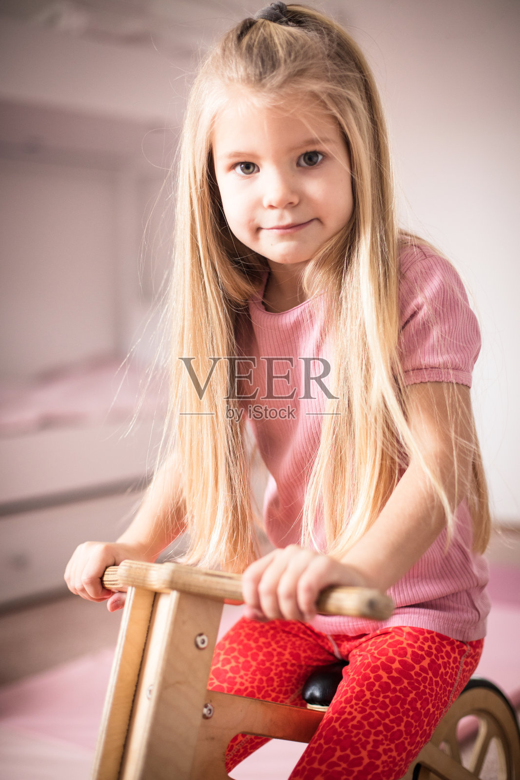 小女孩的房间里有一辆木制自行车。照片摄影图片