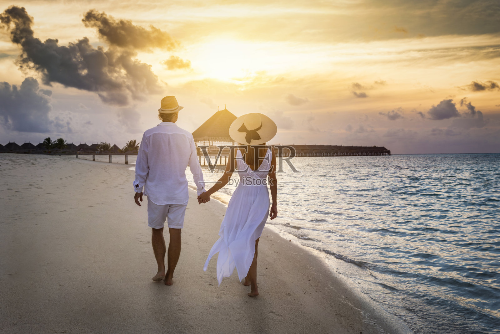 一对旅行者夫妇在日落时分沿着热带海滩散步照片摄影图片