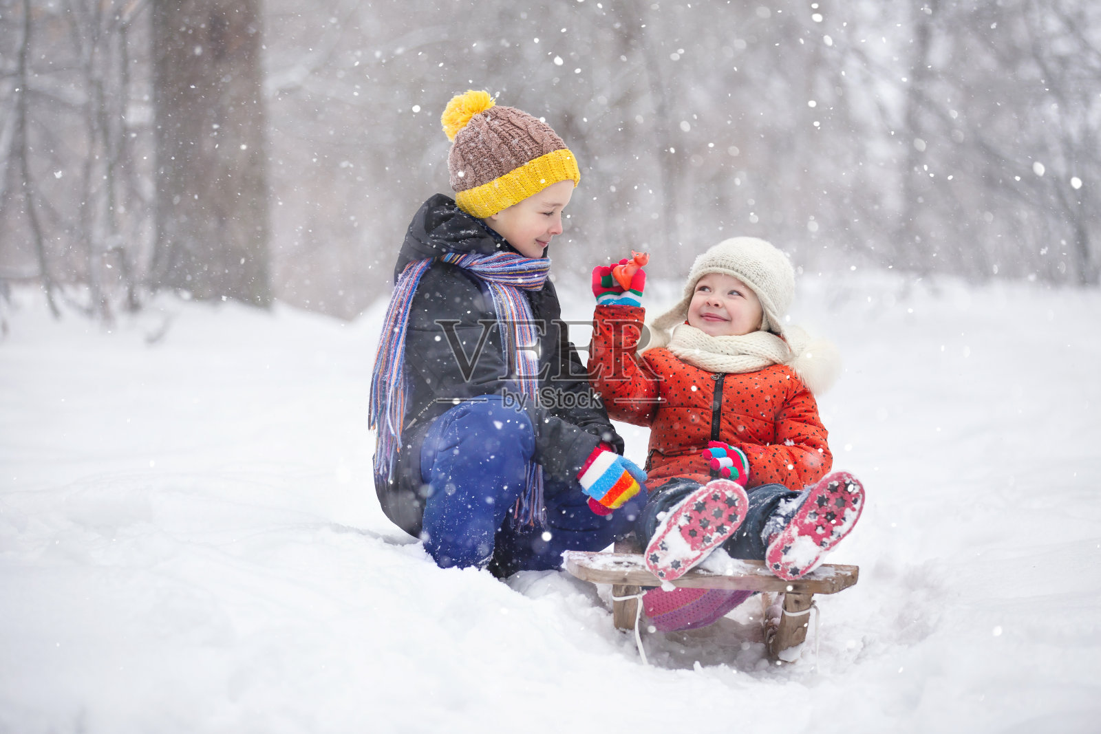 在一个下雪的冬日，一个男孩和他的妹妹在公园里散步照片摄影图片
