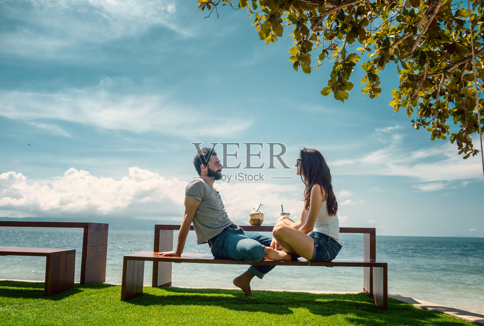 幸福的年轻美丽的情侣在热带度假胜地享受假期喝鸡尾酒与海景的海滩照片摄影图片