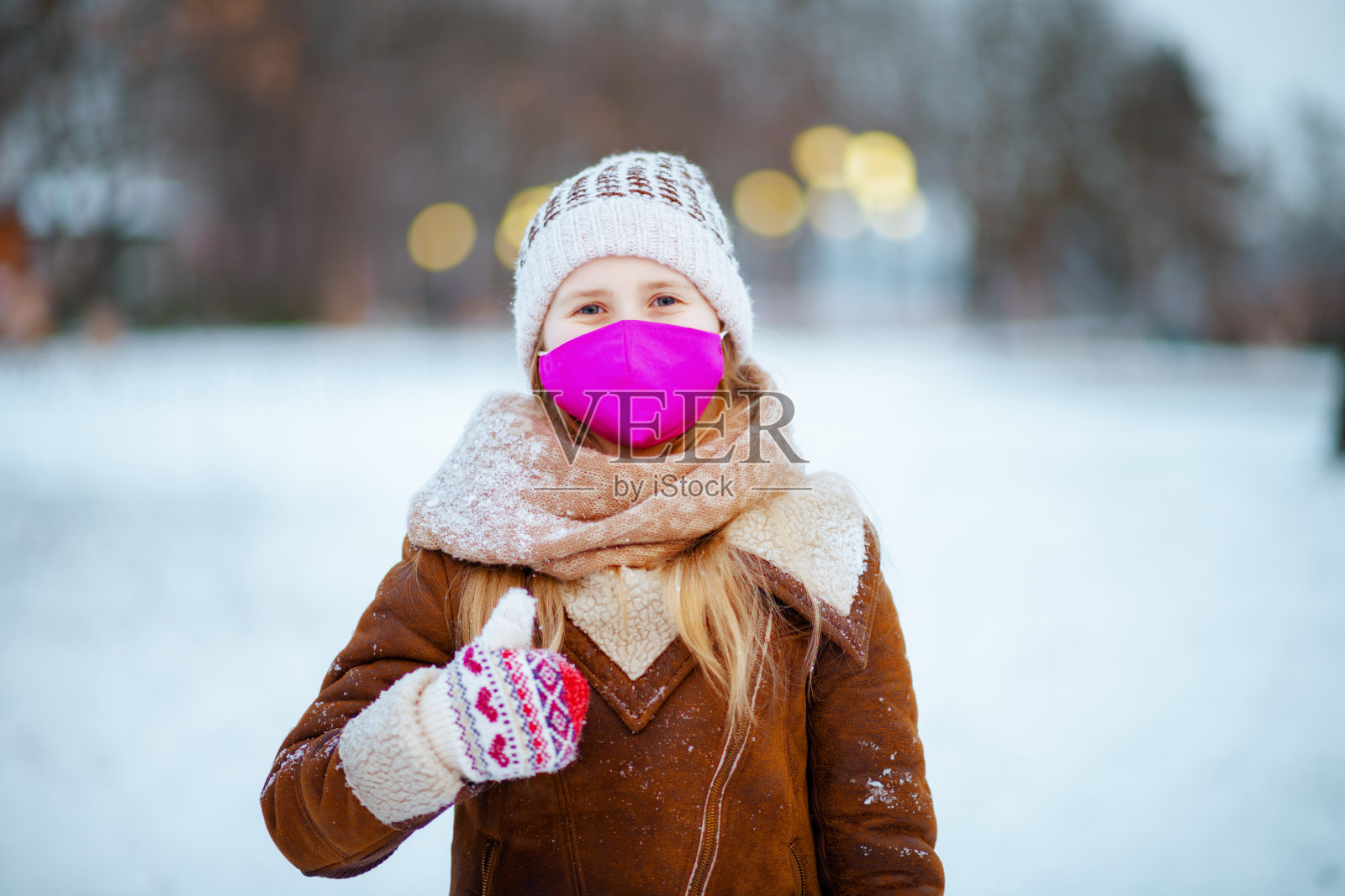 微笑的女孩在城市公园外竖起大拇指在冬天照片摄影图片