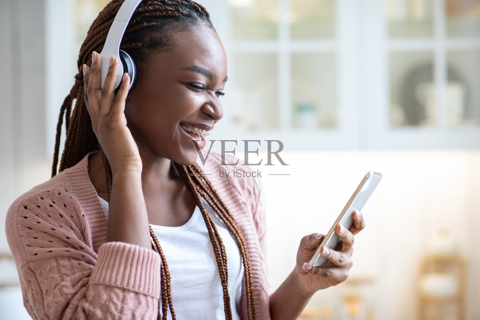 休闲消遣。欢快的非洲裔美国女性用耳机和智能手机听音乐照片摄影图片