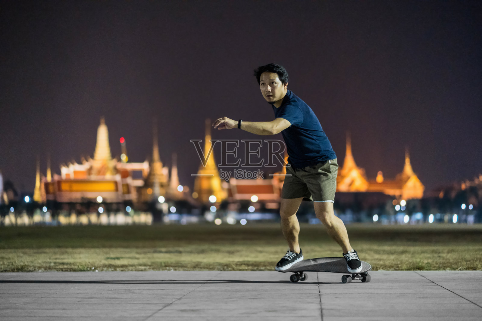 亚洲人在户外公园玩冲浪或滑板，在照片模糊的曼谷大皇宫，泰国，低光，极限运动，健康和运动，时尚的新冠概念照片摄影图片