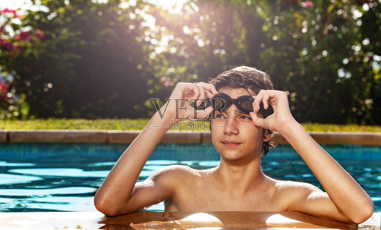 一个十几岁的男孩在游泳池边上照片摄影图片