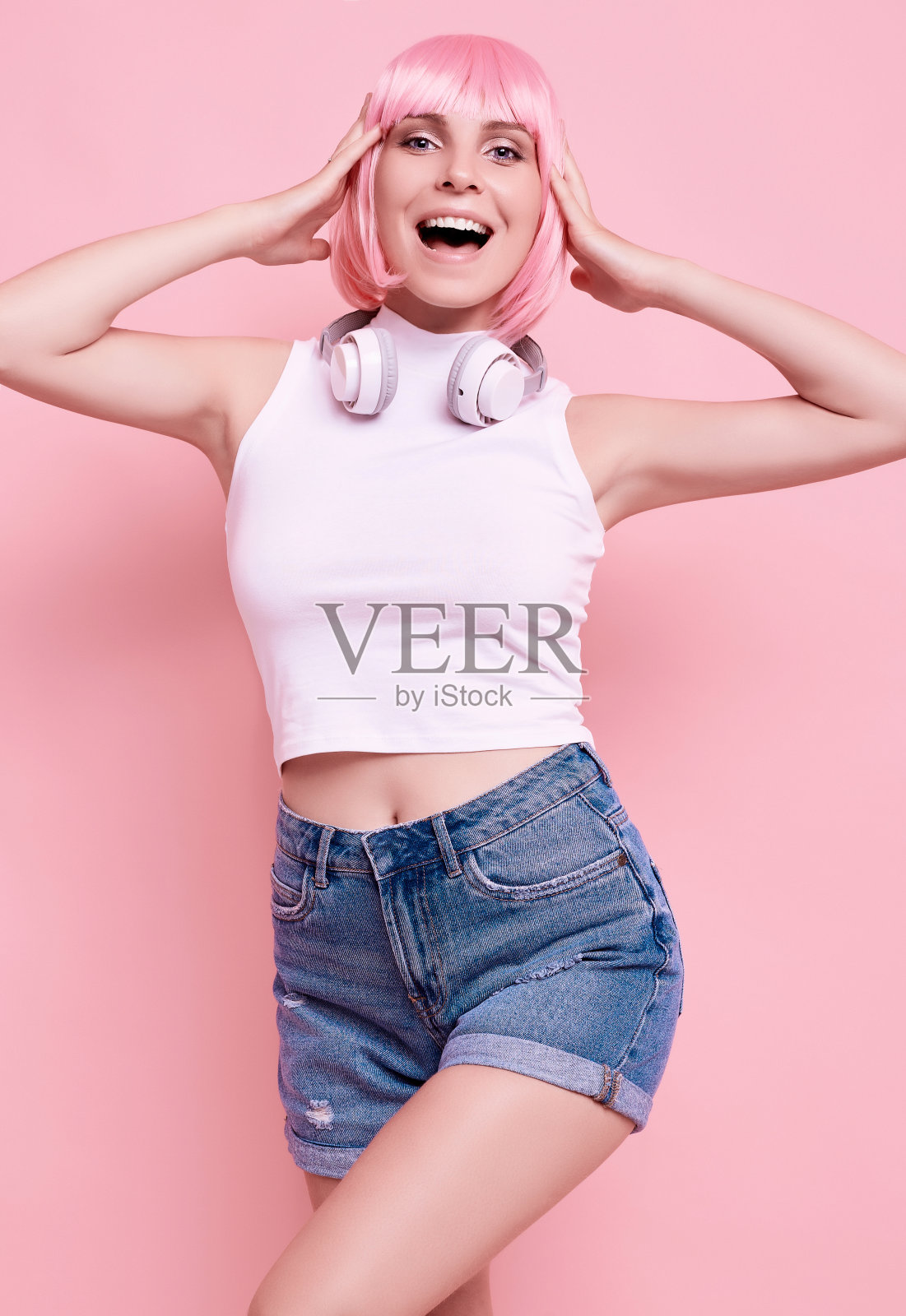 亮粉色头发的时髦女孩戴着耳机听音乐照片摄影图片