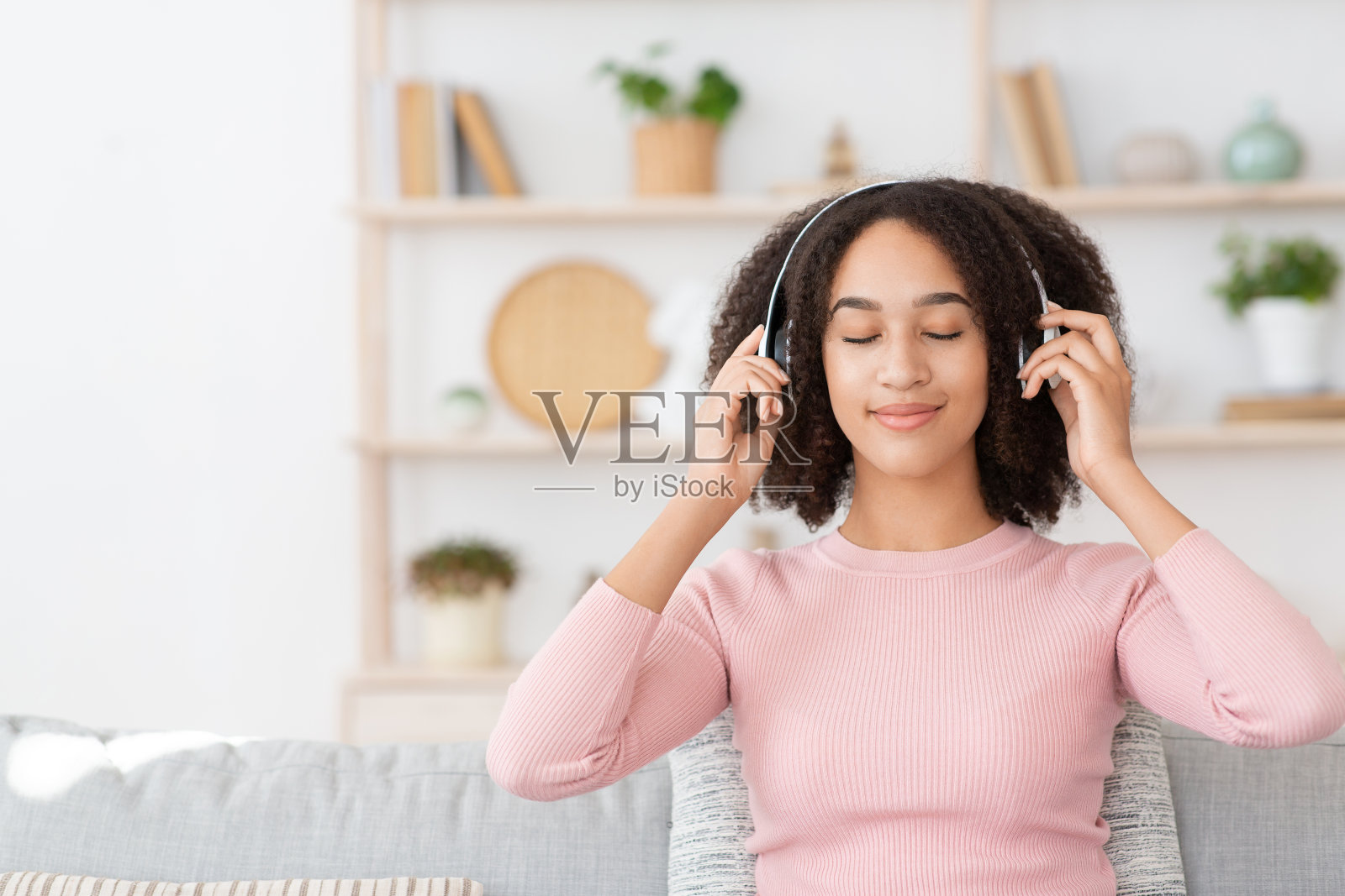 快乐平静的千禧一代非洲裔美国女性闭着眼睛，戴着现代耳机照片摄影图片