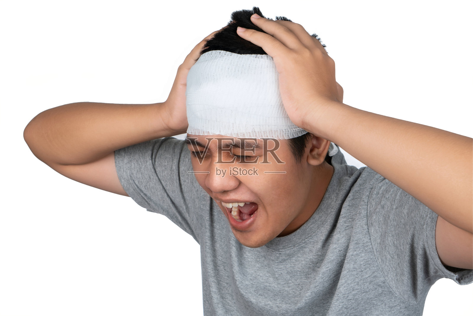 亚洲男孩在头上缠绷带，大声喊叫或对辱骂他的人感到害怕。非常痛头痛。受伤的年轻人，头上缠着绷带。照片摄影图片