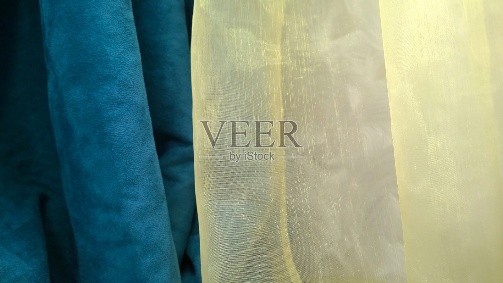 明亮的黄色豪华薄纱和优雅的天鹅绒深蓝窗帘的细节。为室内设计提供优质材料。精致的织物背景。纺织服装业发展。照片摄影图片