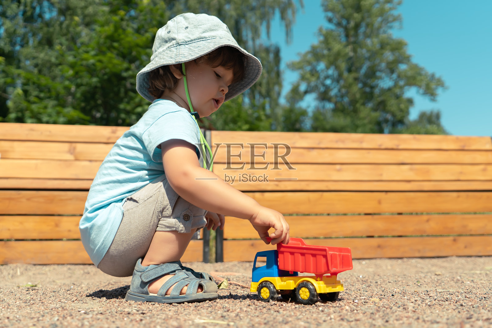 一个小男孩坐在户外玩玩具车的肖像照片摄影图片