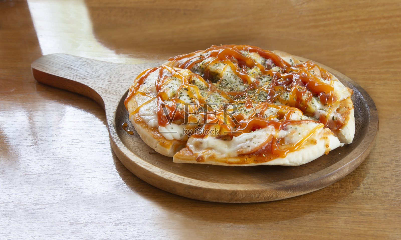 小尺寸的披萨放在木盘子里，一个人吃起来很美味。照片摄影图片