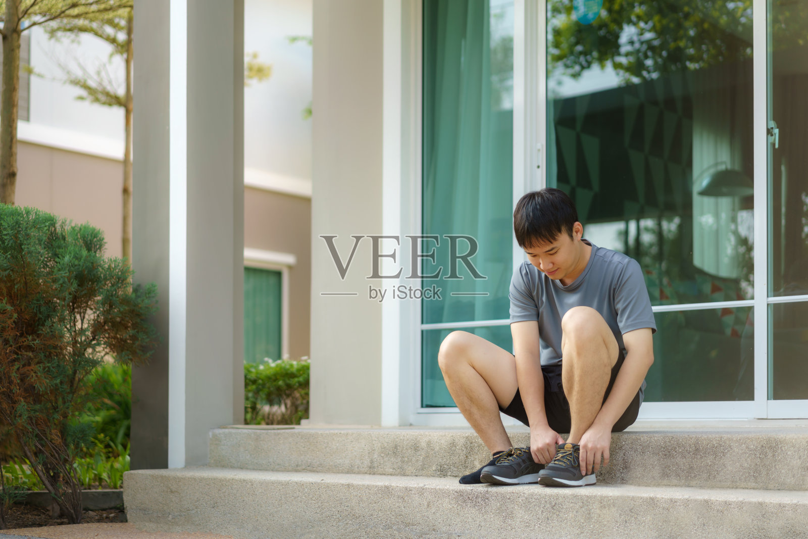 为了身体和精神上的健康和幸福，亚洲男子穿着鞋在家门口的台阶上慢跑。照片摄影图片
