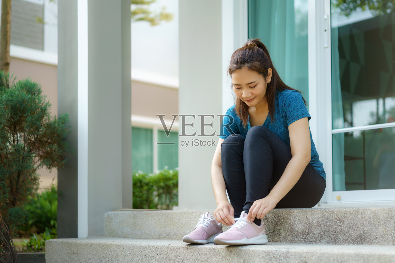 为了身体和精神上的健康和幸福，亚洲妇女穿着鞋子在家门口的台阶上慢跑。照片摄影图片