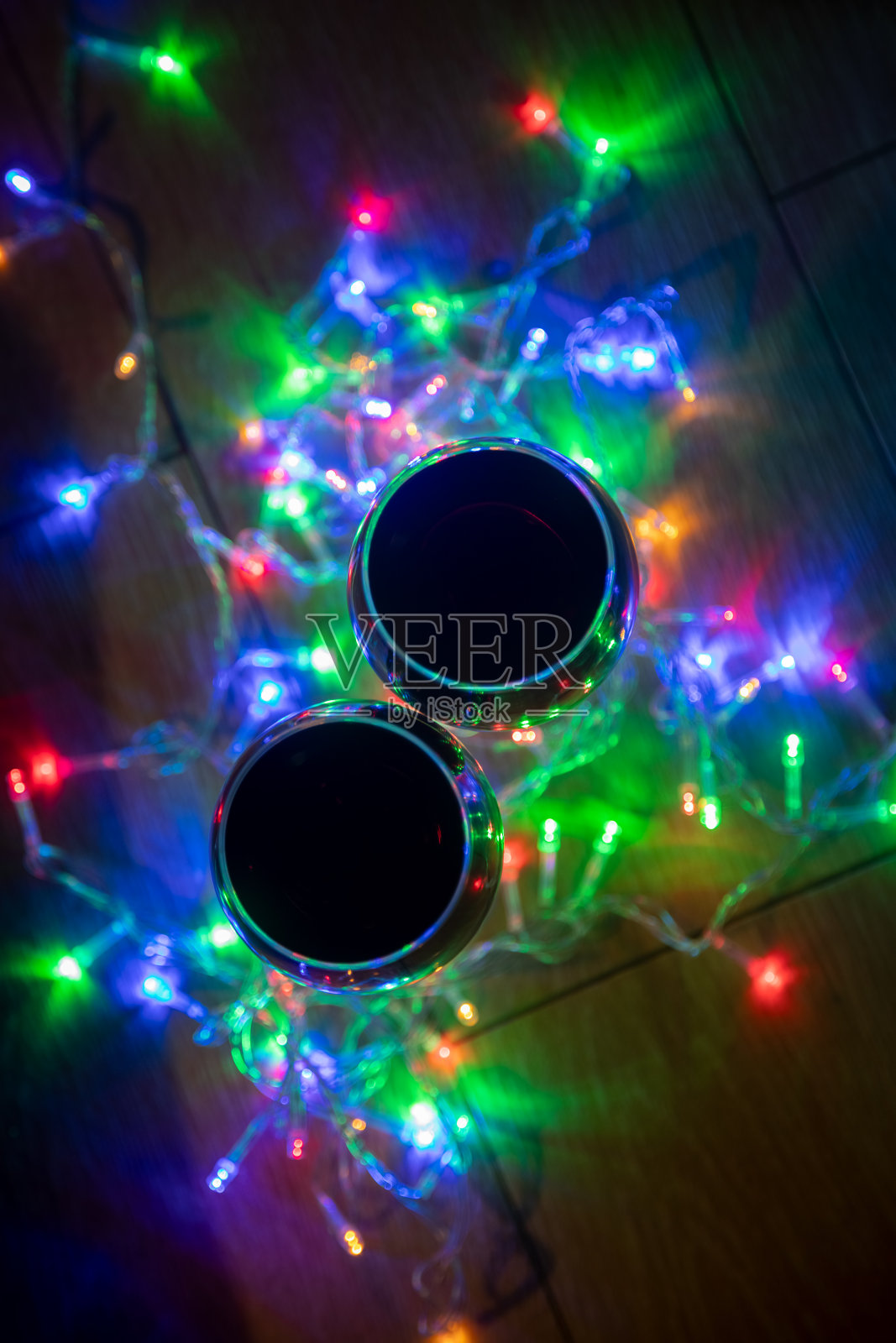 顶视图的玻璃酒杯在闪亮的圣诞花环在黑暗的背景。照片摄影图片