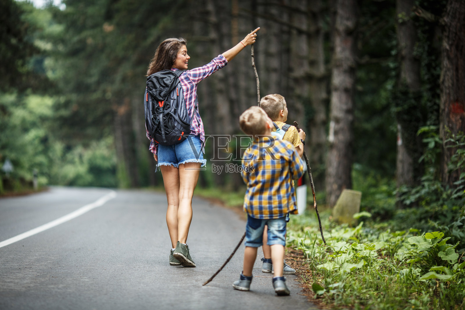母亲和她的小儿子们在乡间小路上徒步旅行。照片摄影图片