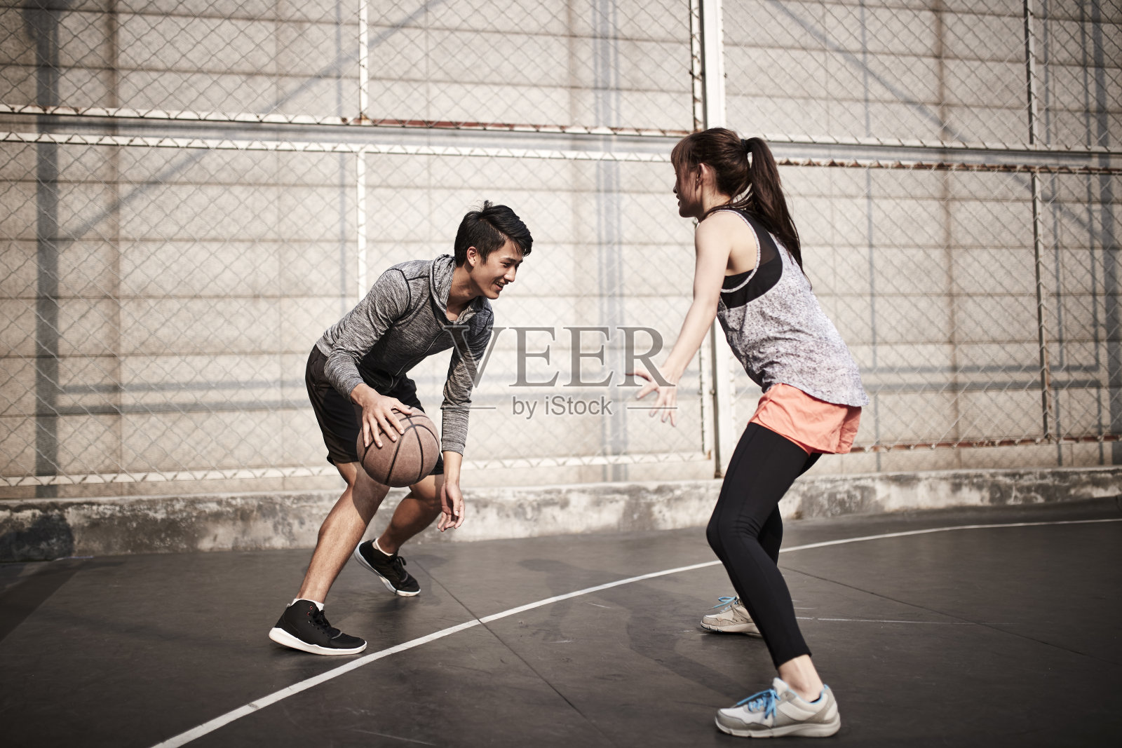 年轻的亚洲夫妇有乐趣打篮球户外照片摄影图片