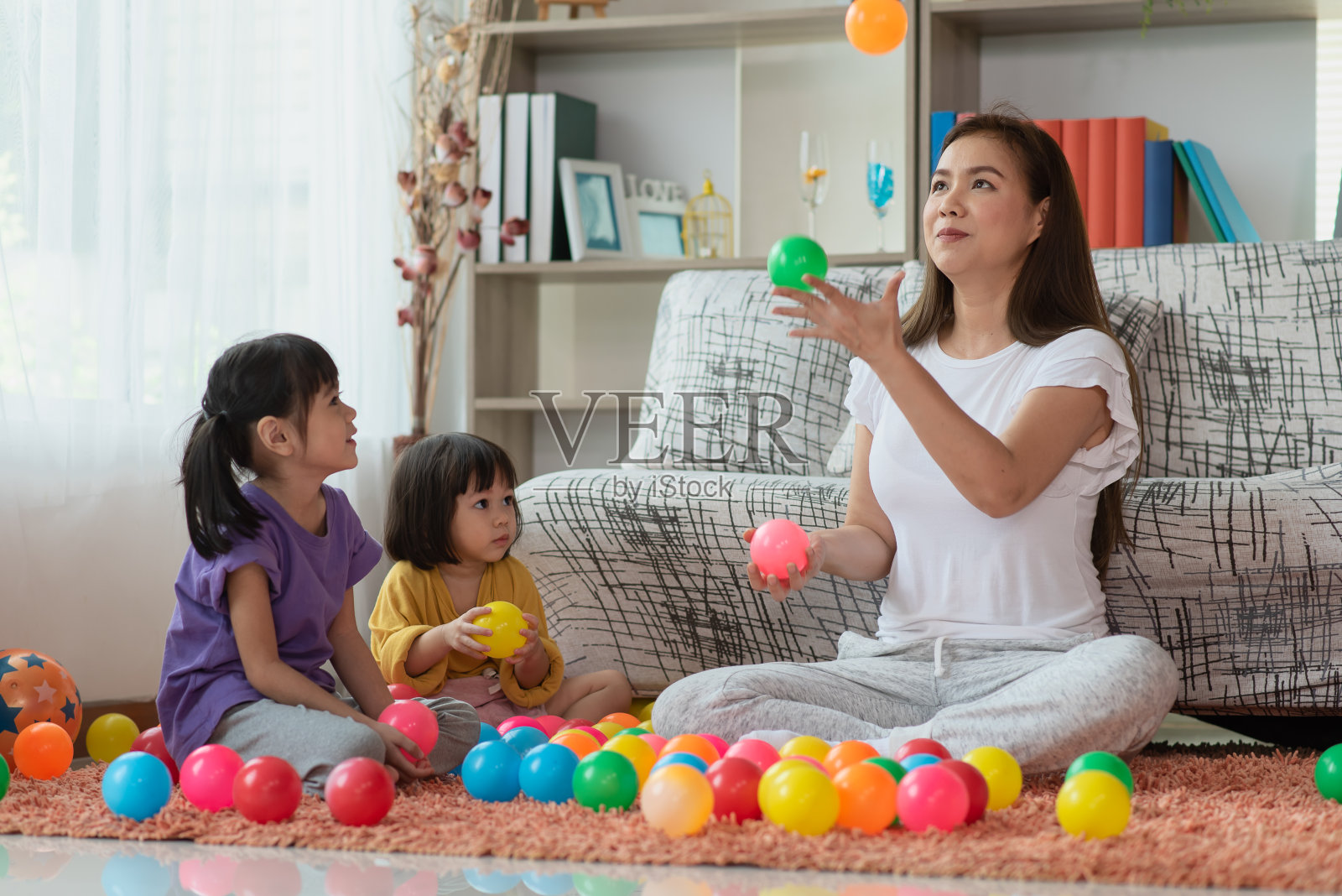 亚洲家庭的母亲和孩子的女儿在玩彩色球照片摄影图片