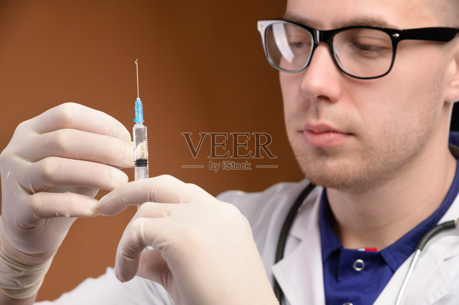 年轻的白人医生，戴着手套，手持注射器。疫苗和疫苗注射概念。专注于脸部照片摄影图片