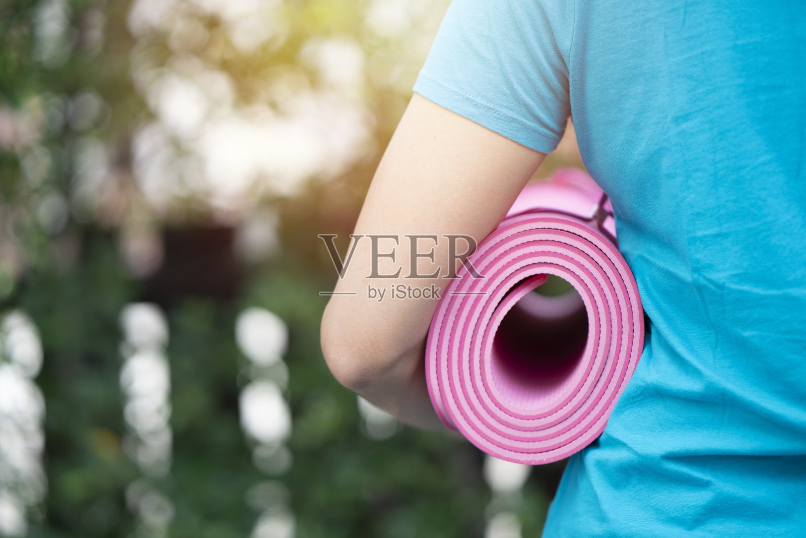 年轻女子抱着瑜伽垫在运动课上为一项运动和健康的概念照片摄影图片