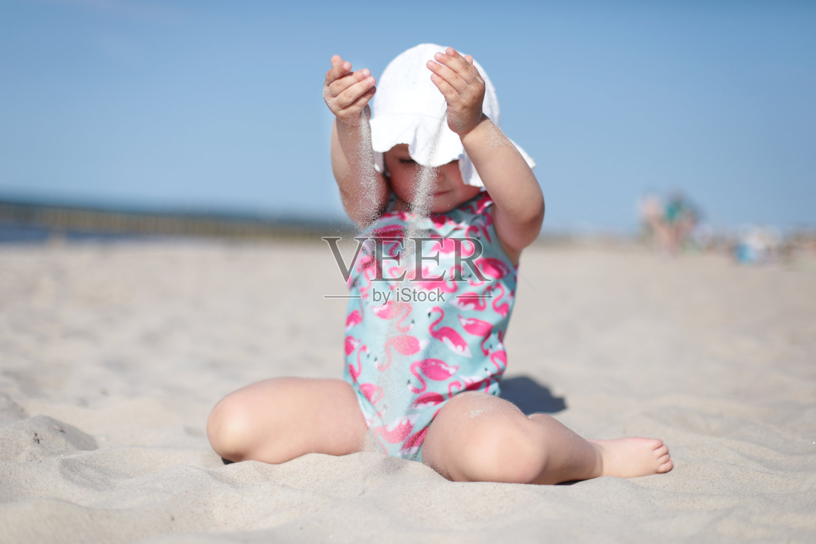 小女孩把白色的沙子倒在沙滩上，享受夏天，度假照片摄影图片