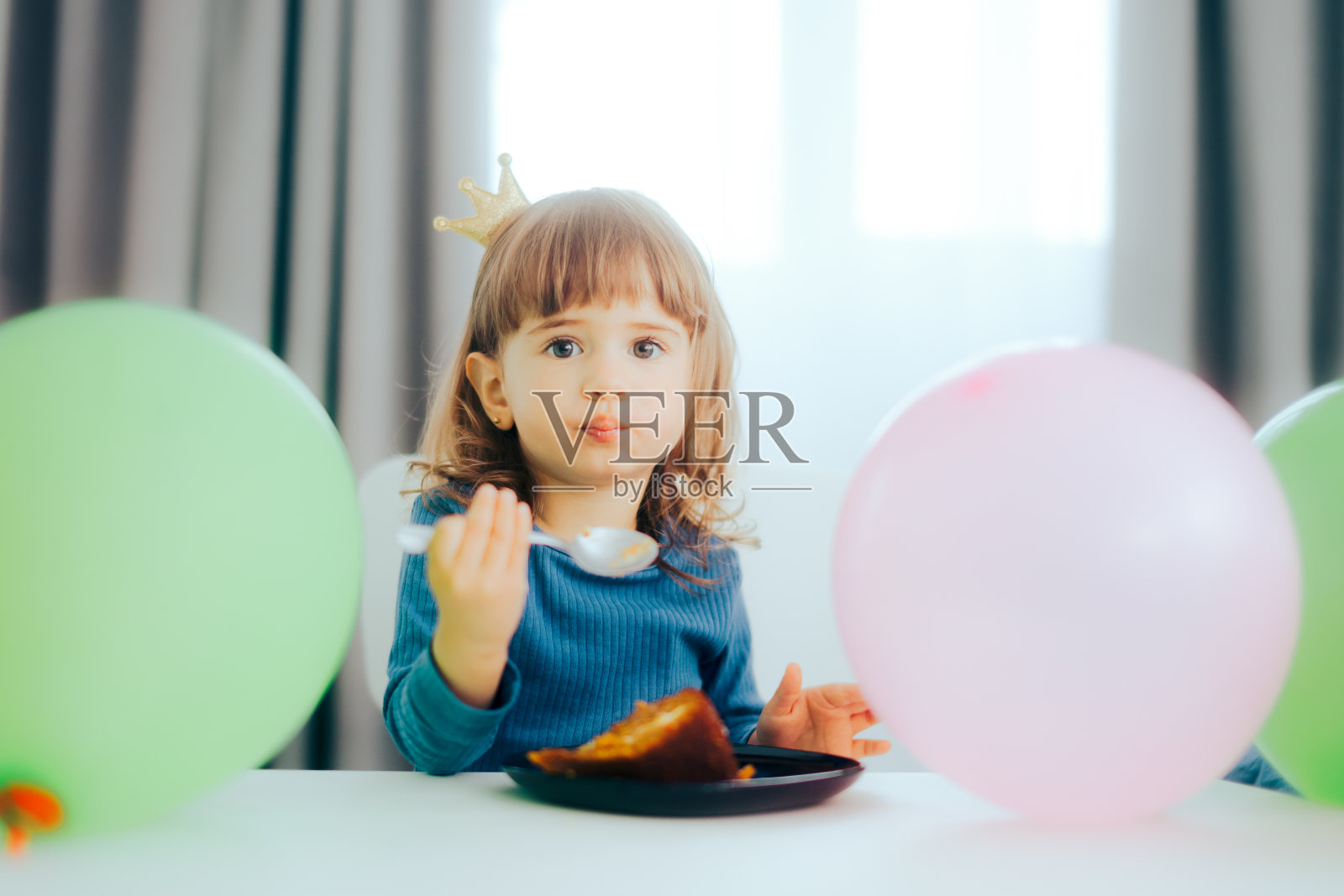 蹒跚学步的小女孩过生日时吃蛋糕照片摄影图片