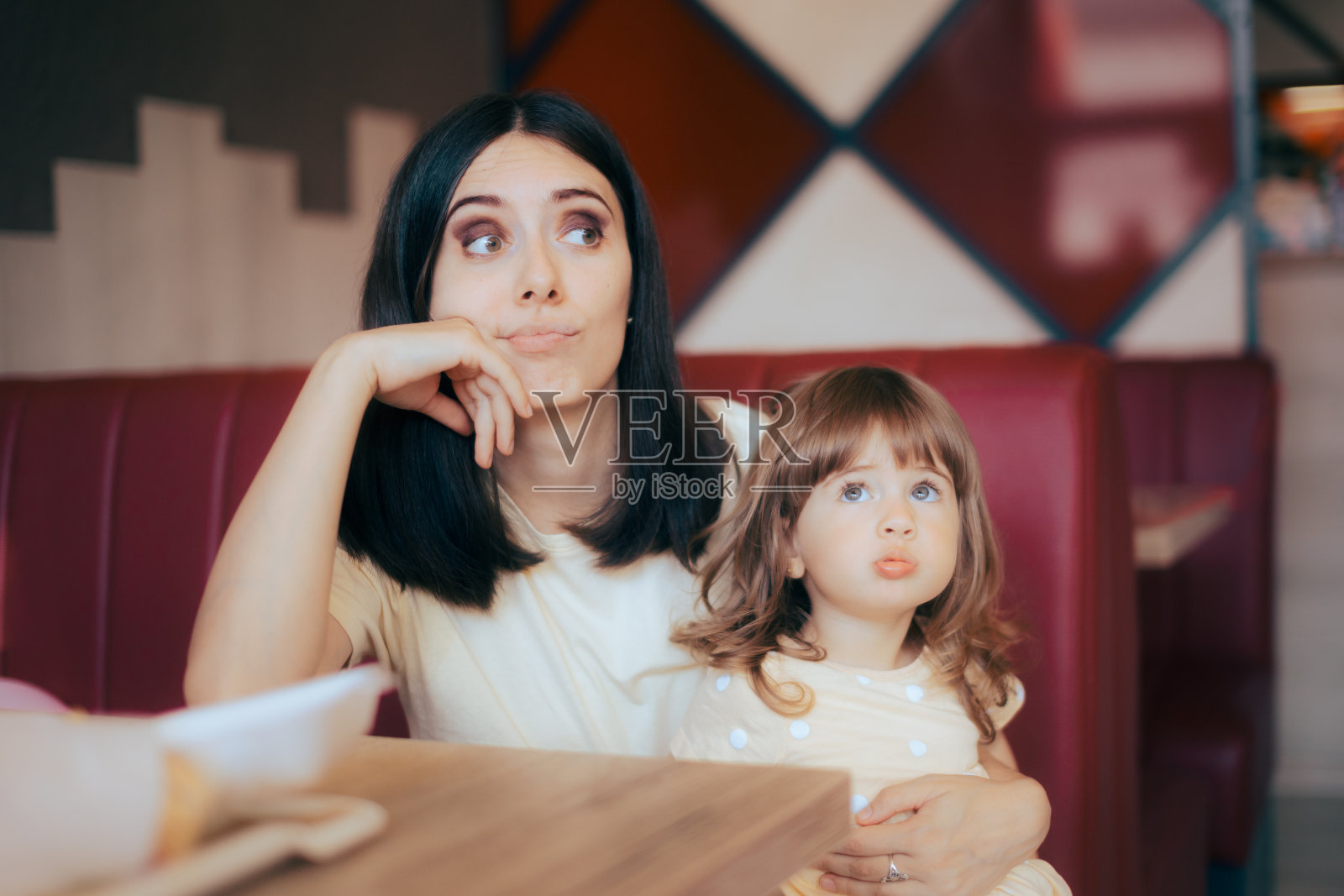 紧张的妈妈和她的孩子坐在餐厅的卡座上照片摄影图片