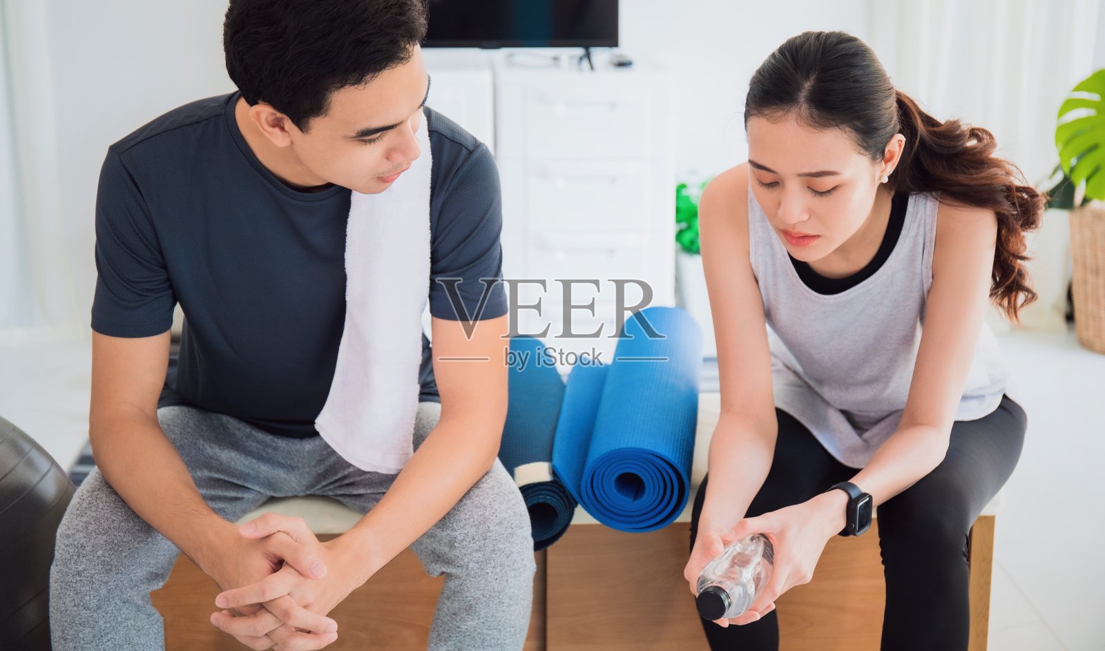 亚洲年轻恋人夫妇聊天后，在家里玩瑜伽和锻炼背景。锻炼身体有利于身体健康，增加柔韧性，收紧身材。照片摄影图片