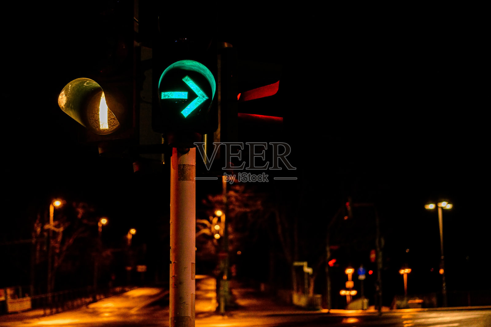 夜晚城市中带有箭头的彩色交通灯的特写照片摄影图片