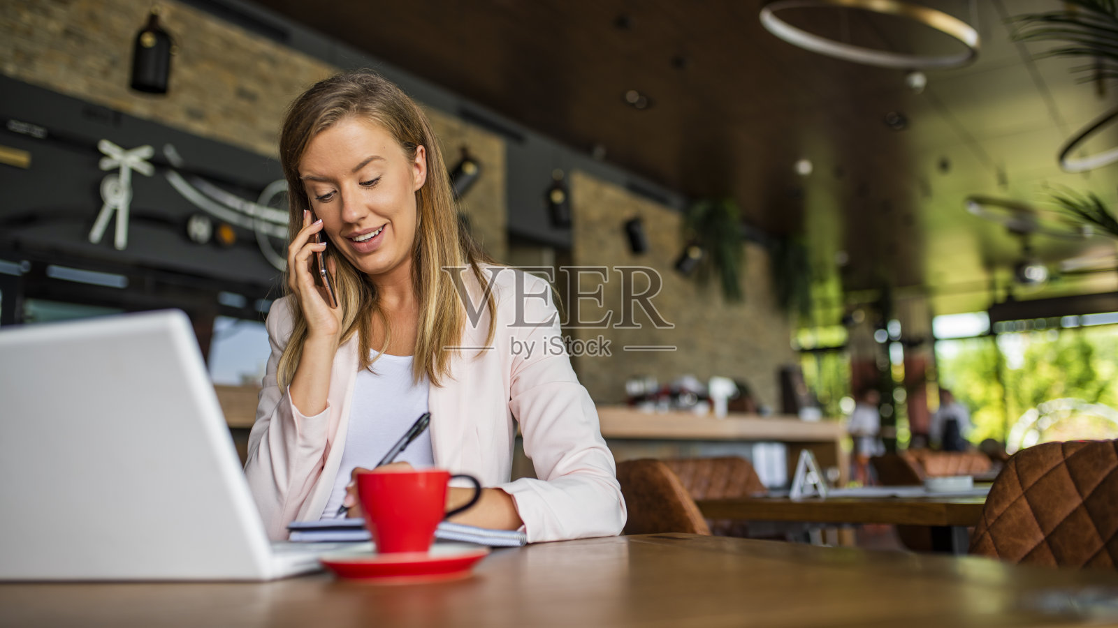 在咖啡馆用笔记本和智能手机的快乐女人照片摄影图片