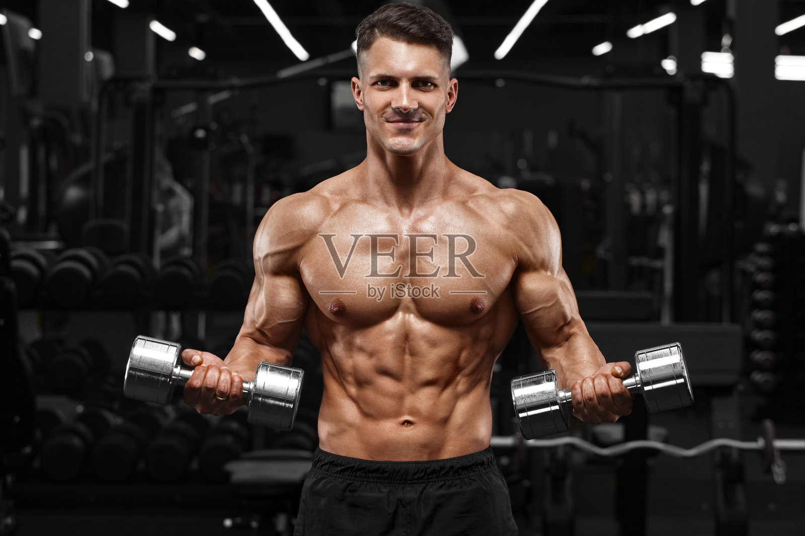 肌肉男在健身房锻炼二头肌，强壮的男性裸露的躯干肌肉照片摄影图片
