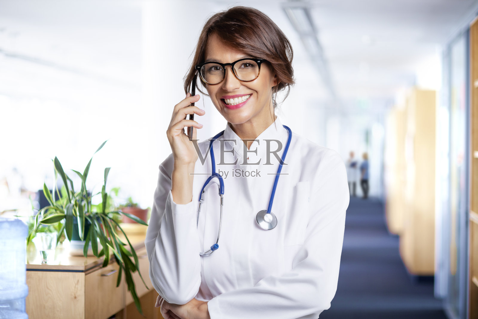 女医生站在诊所的走廊上和她的病人用手机聊天照片摄影图片