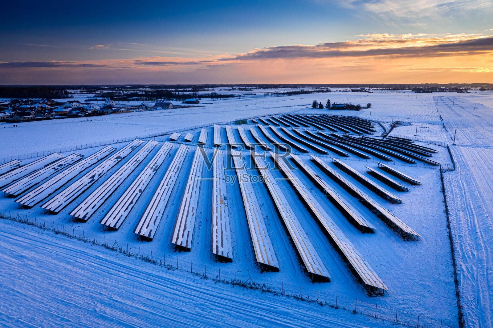 冬天的光伏农场，日落在雪地上照片摄影图片