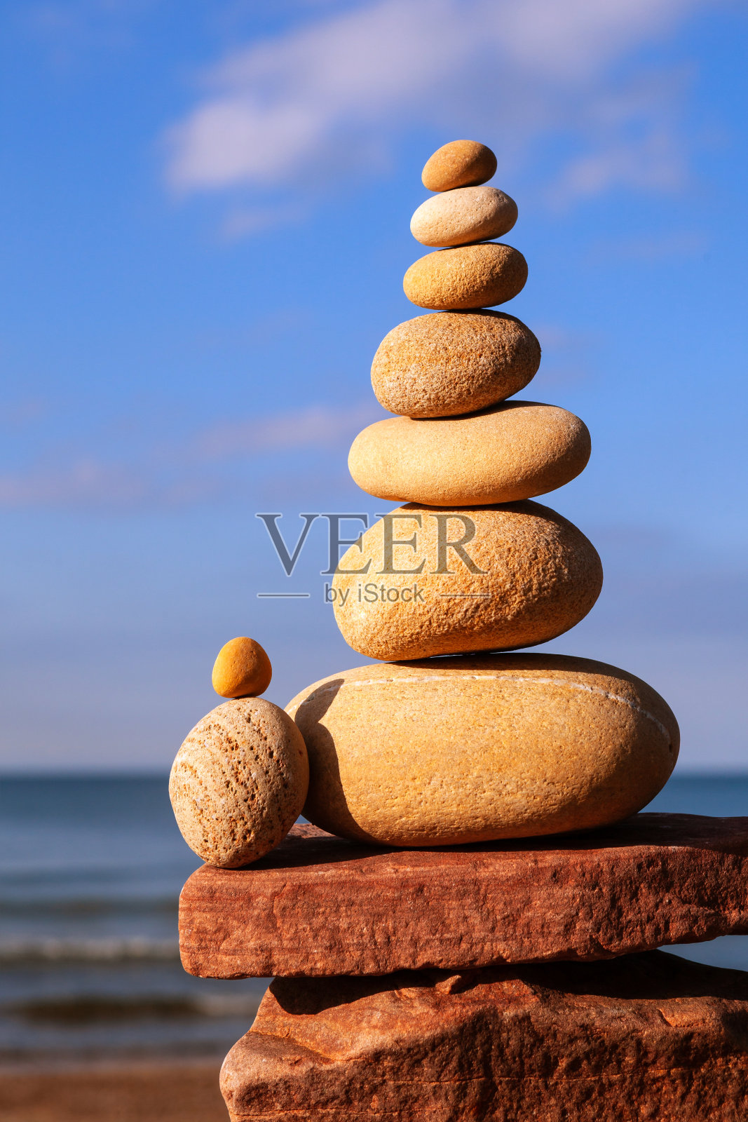 岩石禅金字塔的黄色石头在沙滩上的大海的背景。生活平衡概念照片摄影图片