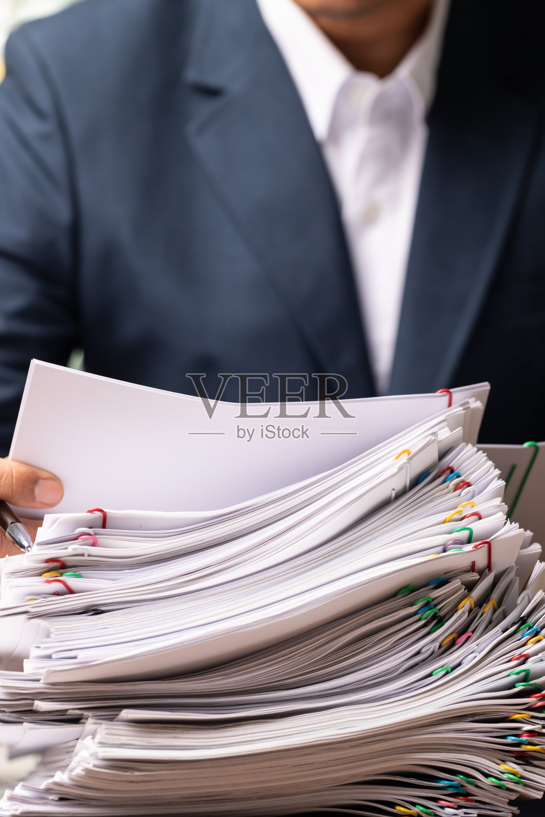 业务人员在办公桌上垂直打开文件报告，业务超负荷纸张堆叠。照片摄影图片