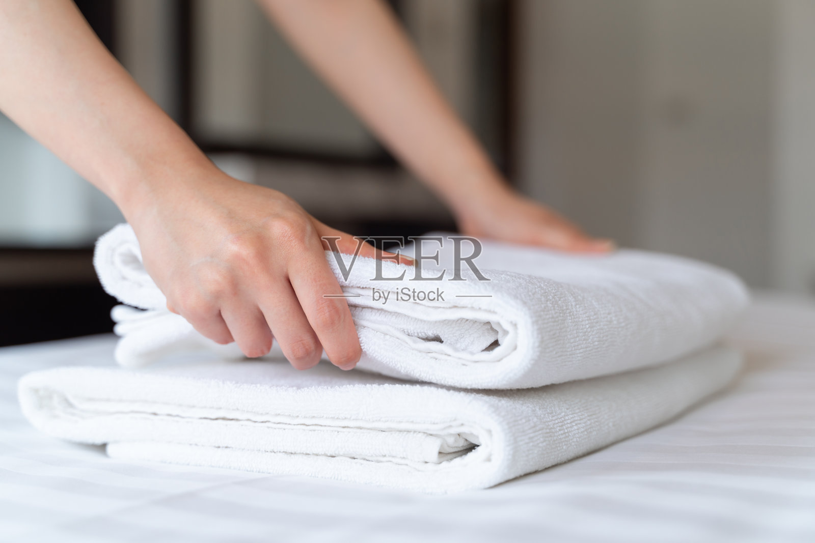 特写手把一叠新的干净的浴巾放在床上。酒店客房服务理念。照片摄影图片